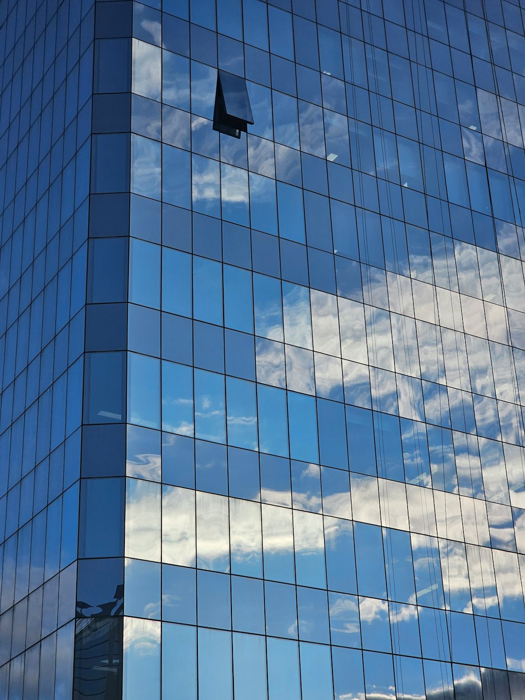 Spiegelnde Glasfenster eines modernen Bürogebäudes spiegeln den Himmel.