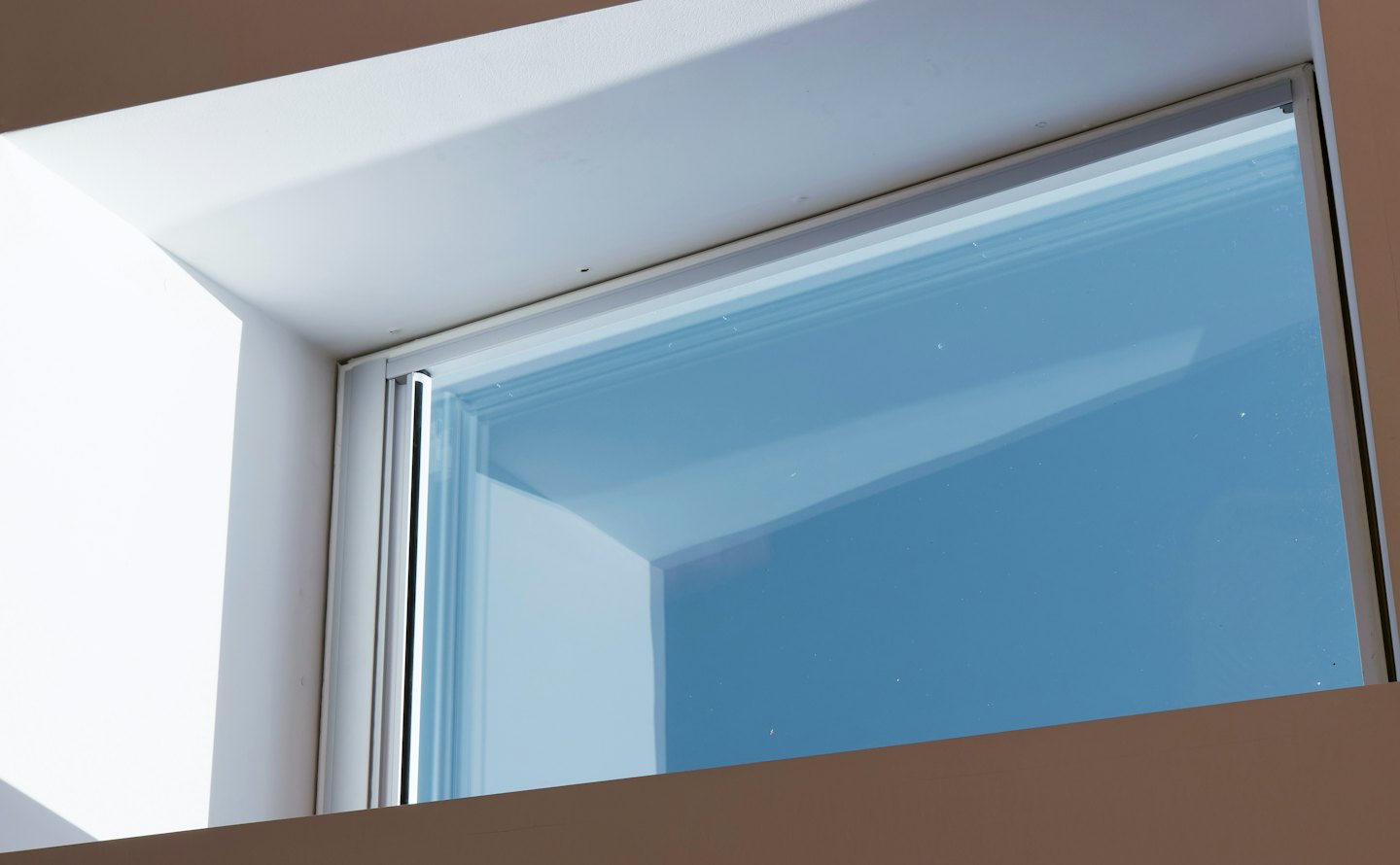 Moderner Fensterrahmen mit Blick auf einen klaren blauen Himmel.